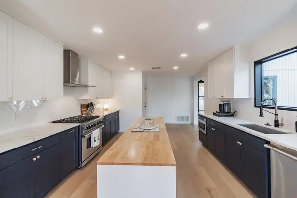 a large kitchen with stainless steel appliances granite countertop a sink counter space and a stove top oven
