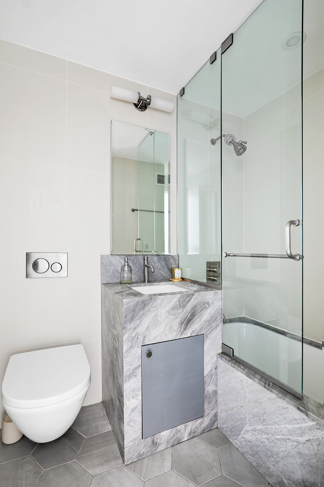 712 Washington Street, Unit 2A Manhattan, NY 10014 - Photo 5 of 8 a spacious bathroom with a granite countertop sink mirror vanity and toilet