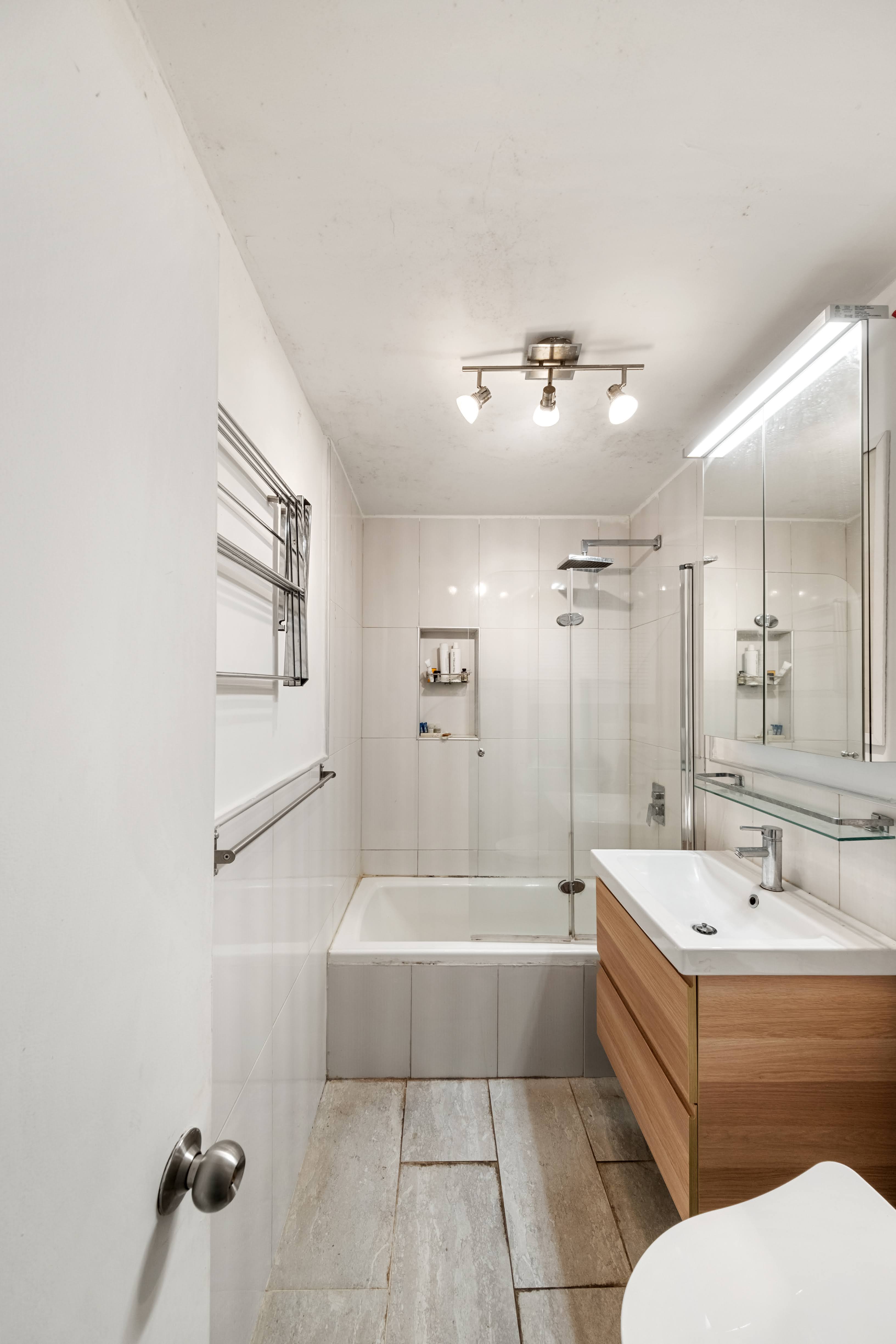 376 Broadway, Unit 4F Manhattan, NY 10013 - Photo 10 of 16 a bathroom with a bathtub a sink a mirror and a shower