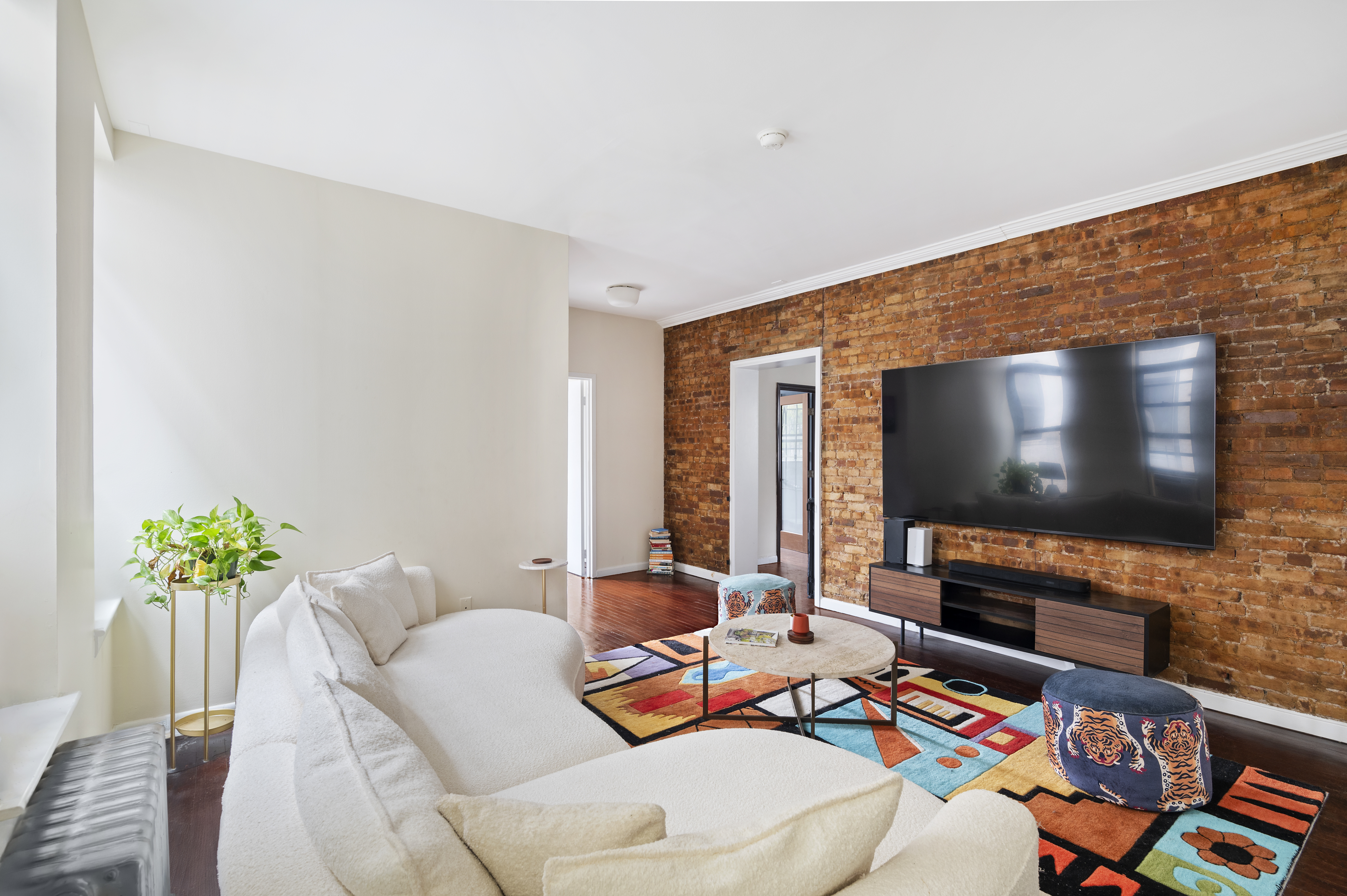 11 St Nicholas Avenue, Unit 5A/5H Manhattan, NY 10026 - Photo 2 of 6 a living room with furniture and a flat screen tv