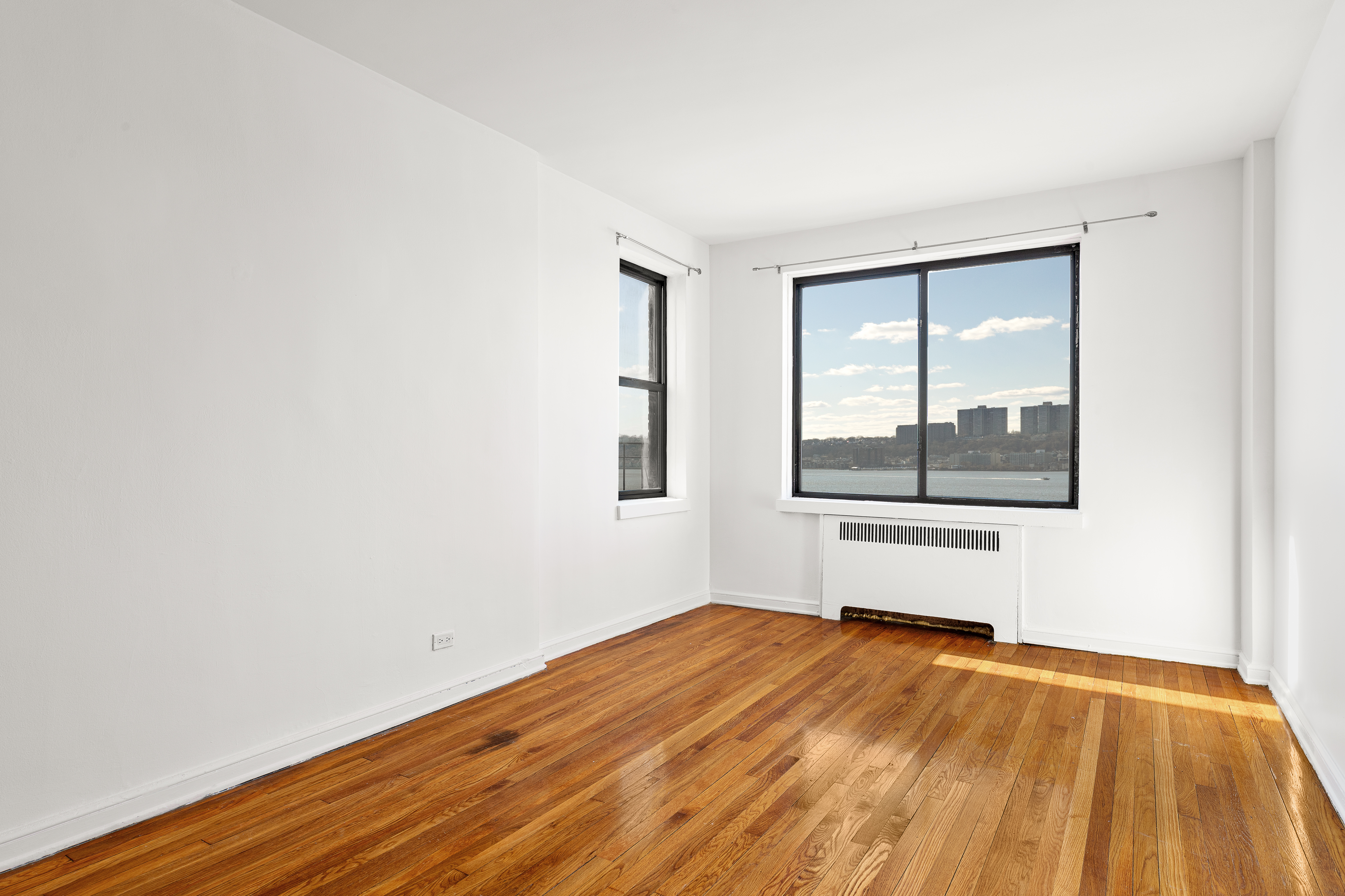 158-18 Riverside Drive West, Unit 4E50 Manhattan, NY 10032 - Photo 8 of 17 an empty room with wooden floor and windows