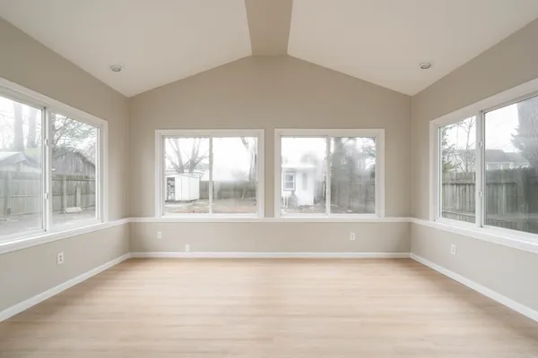 a view of an empty room with a window and a kitchen