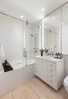 a bathroom with a tub sink double vanity and a mirror