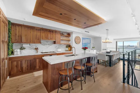 a kitchen with stainless steel appliances kitchen island granite countertop a table chairs sink and cabinets
