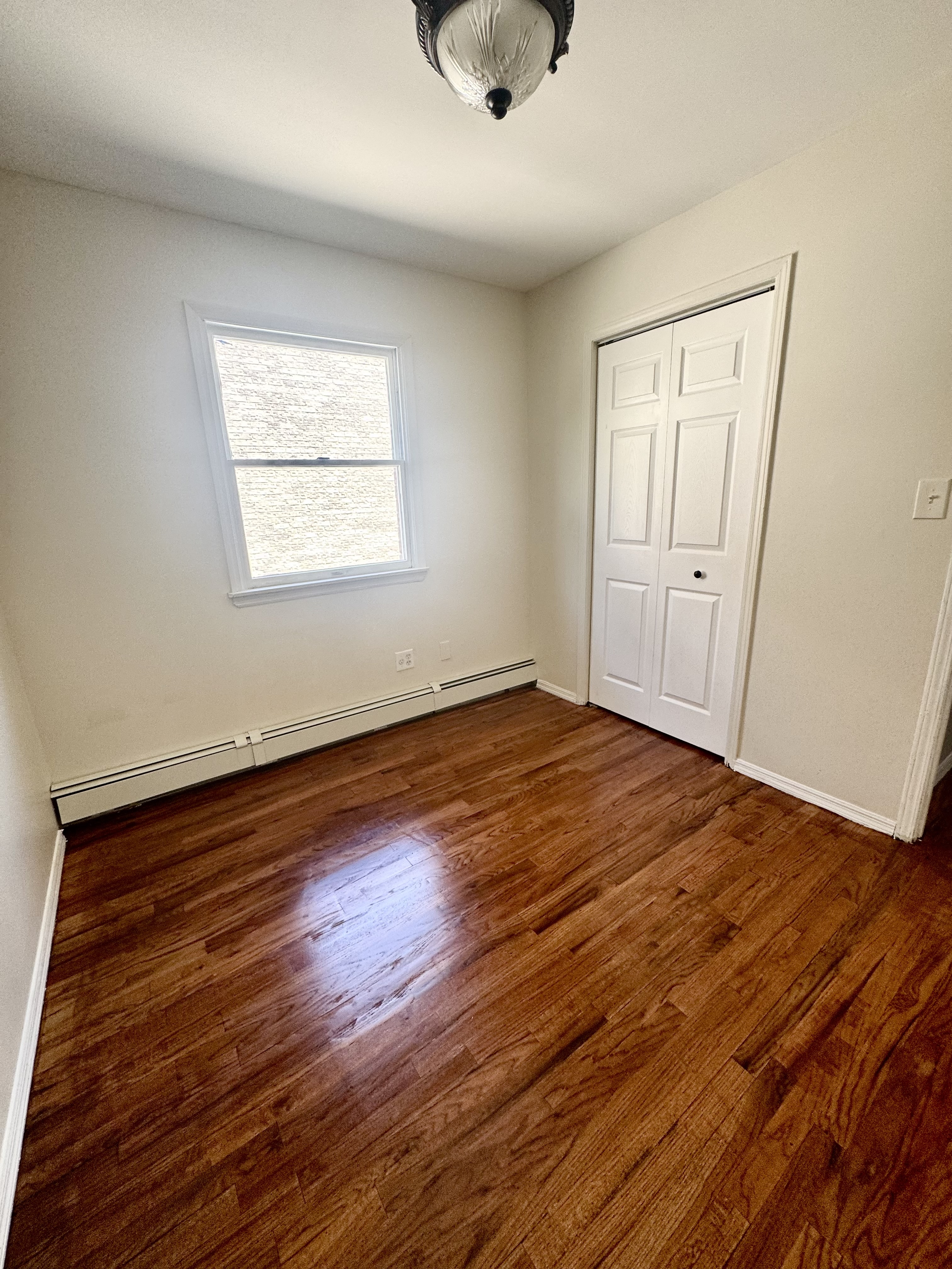 156-17 76th Street, Unit 1 Queens, NY 11414 - Photo 6 of 12 an empty room with wooden floor and windows