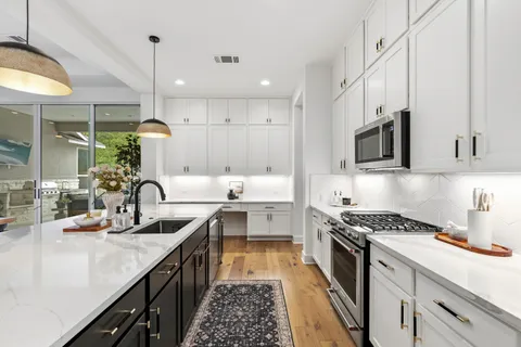a kitchen with kitchen island granite countertop a sink a counter space stainless steel appliances and cabinets