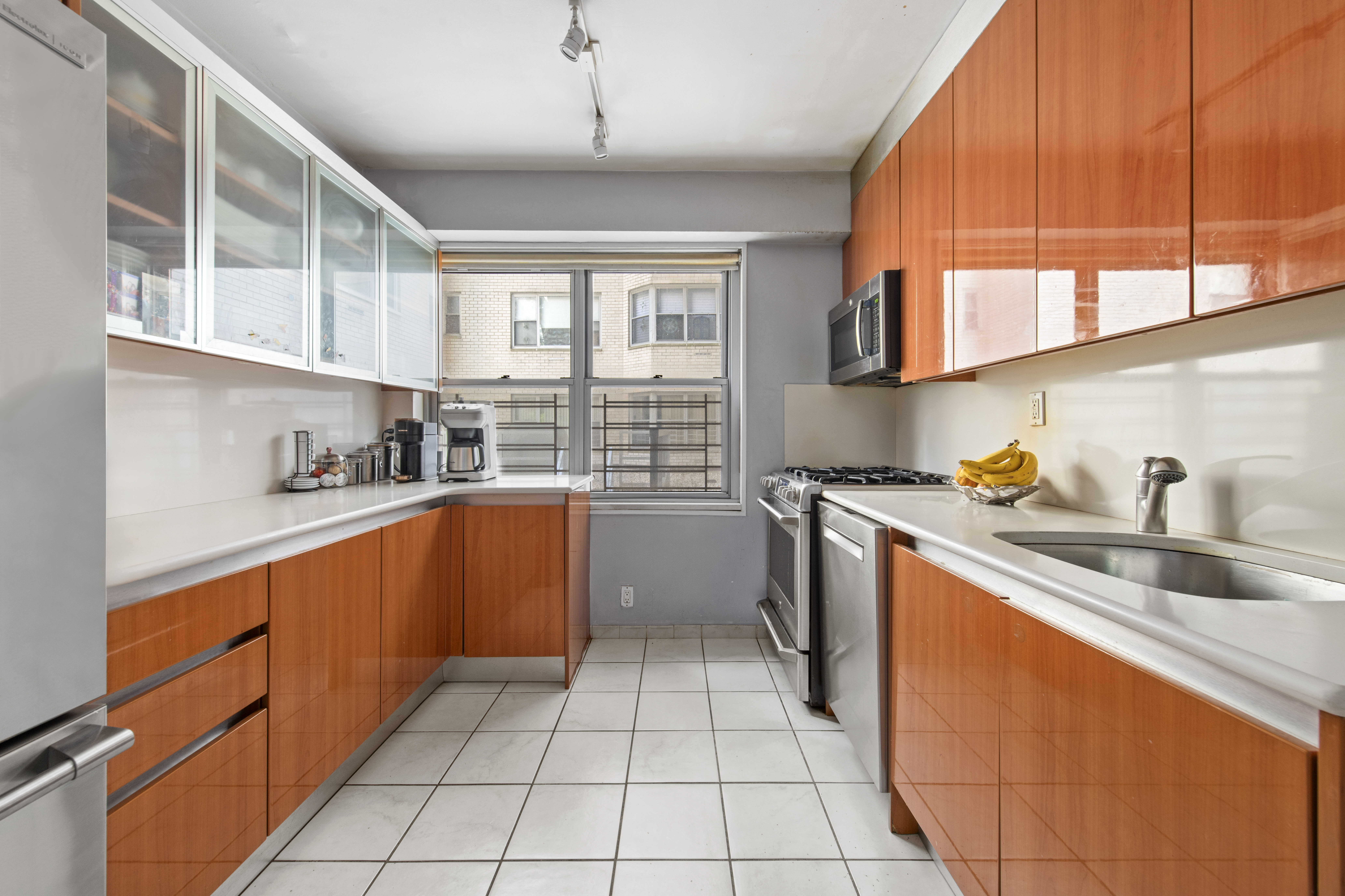 400 East 56th Street, Unit 3D Manhattan, NY 10022 - Photo 10 of 24 a kitchen with stainless steel appliances granite countertop a sink counter space cabinets and a large window