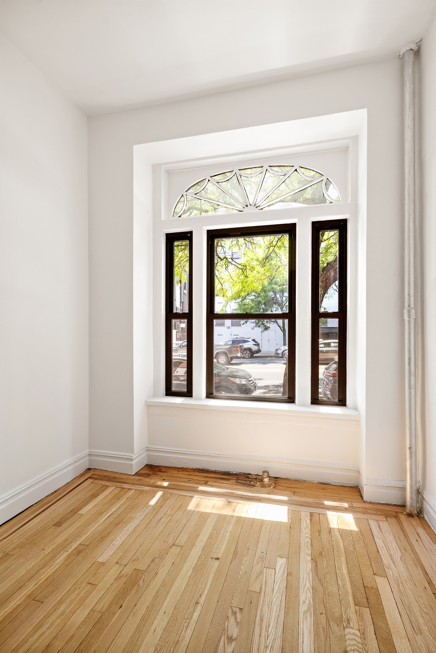 107 West 106th Street, Unit D Manhattan, NY 10025 - Photo 5 of 12 an empty room with wooden floor and a window