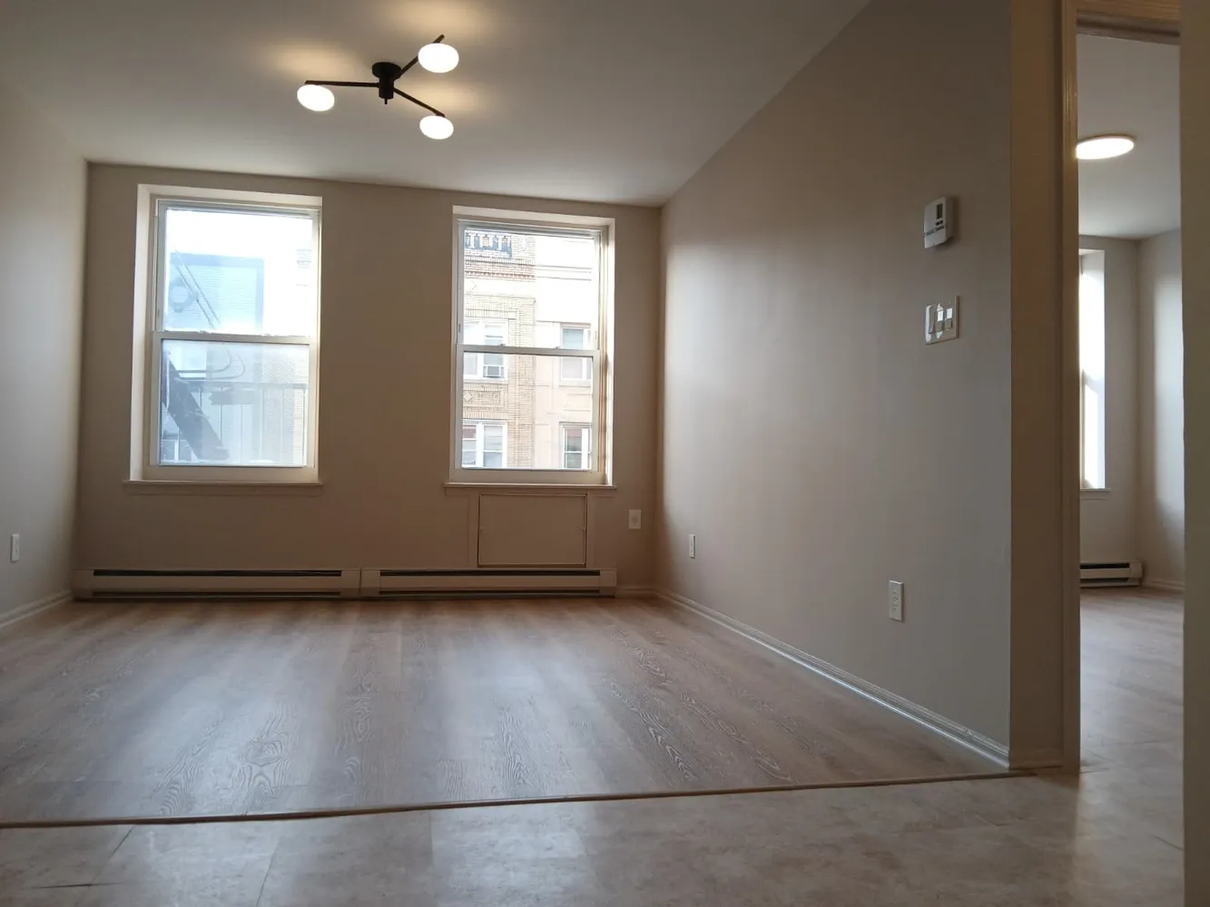 an empty room with wooden floor and windows