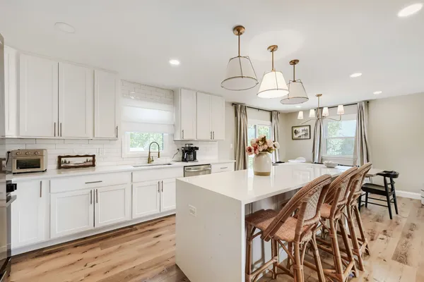 a kitchen with stainless steel appliances a sink a stove a refrigerator and white cabinets with wooden floor