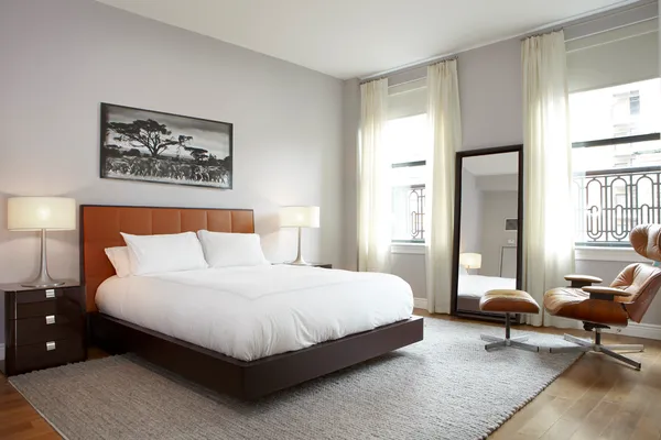 a bedroom with a bed a lamp on desk and a window
