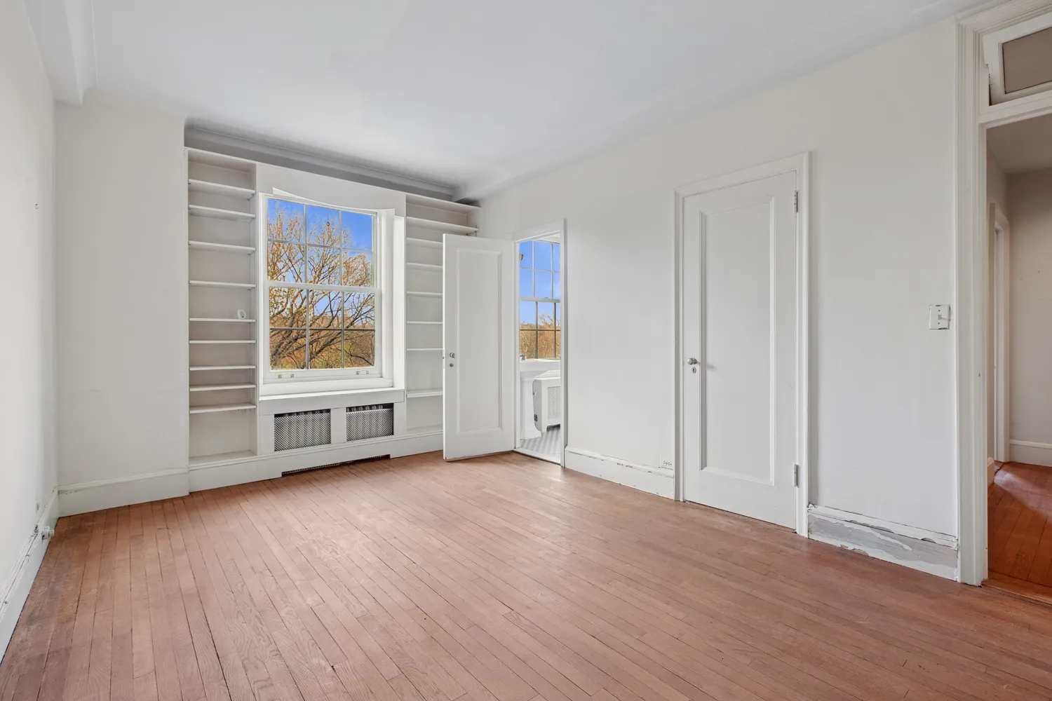 an empty room with wooden floor and window