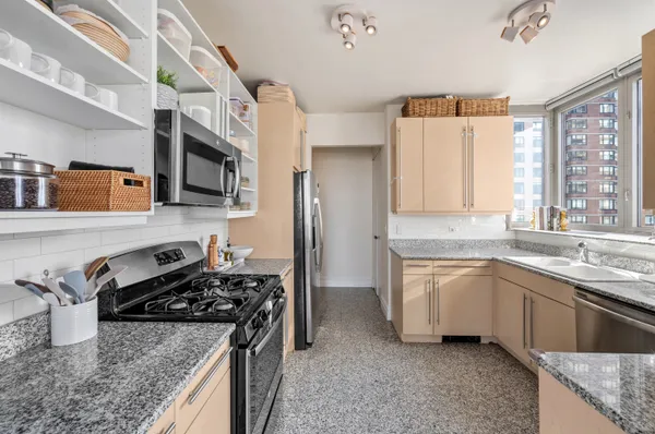 a kitchen with stainless steel appliances granite countertop a stove a sink and a microwave