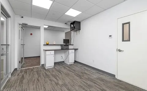 a room with wooden floor and white cabinets