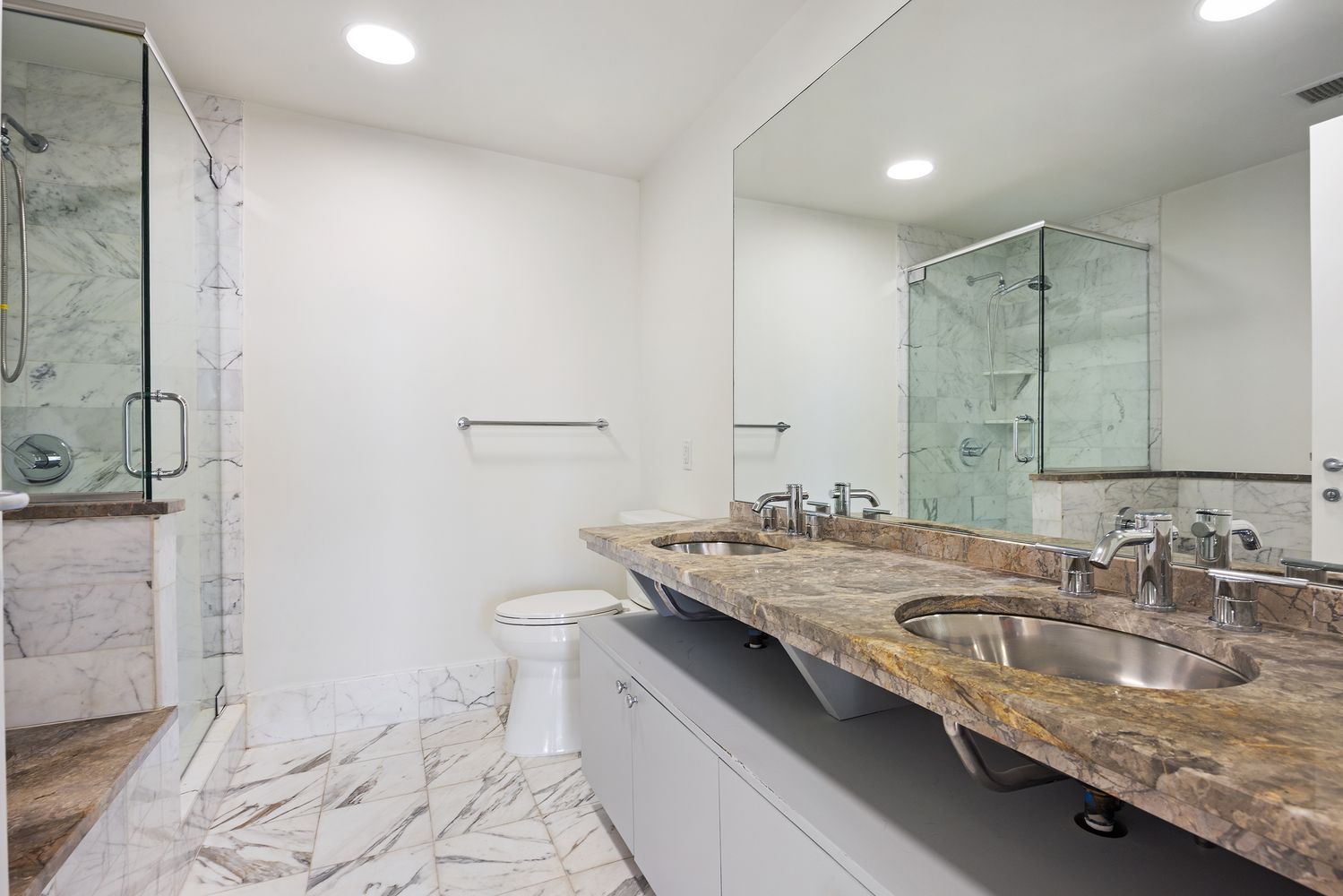 a bathroom with a granite countertop sink a toilet a mirror and shower