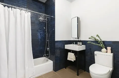 a bathroom with a sink a toilet a mirror and shower