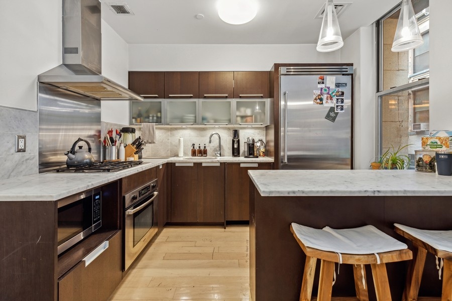 119 Fulton Street, Unit 2B Manhattan, NY 10038 - Photo 1 of 10 a kitchen with stainless steel appliances granite countertop table chairs sink and cabinets