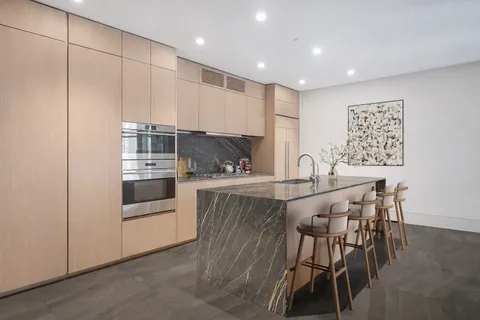 a kitchen with kitchen island a white counter top space and stainless steel appliances