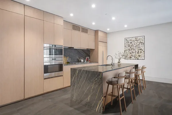 a kitchen with kitchen island a white counter top space and stainless steel appliances