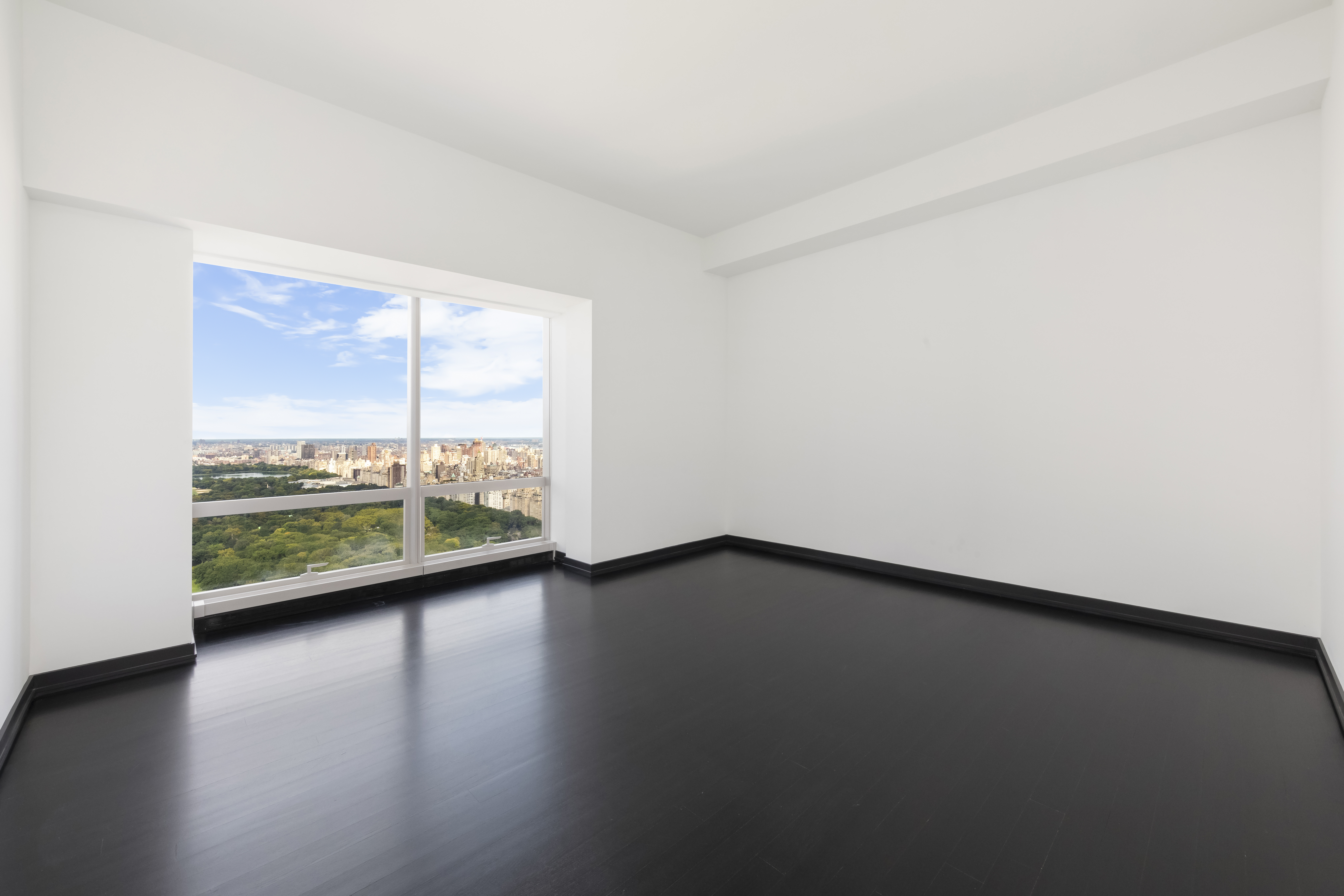 157 West 57th Street, Unit 56C Manhattan, NY 10019 - Photo 7 of 12 a view of an empty room with wooden floor and a window
