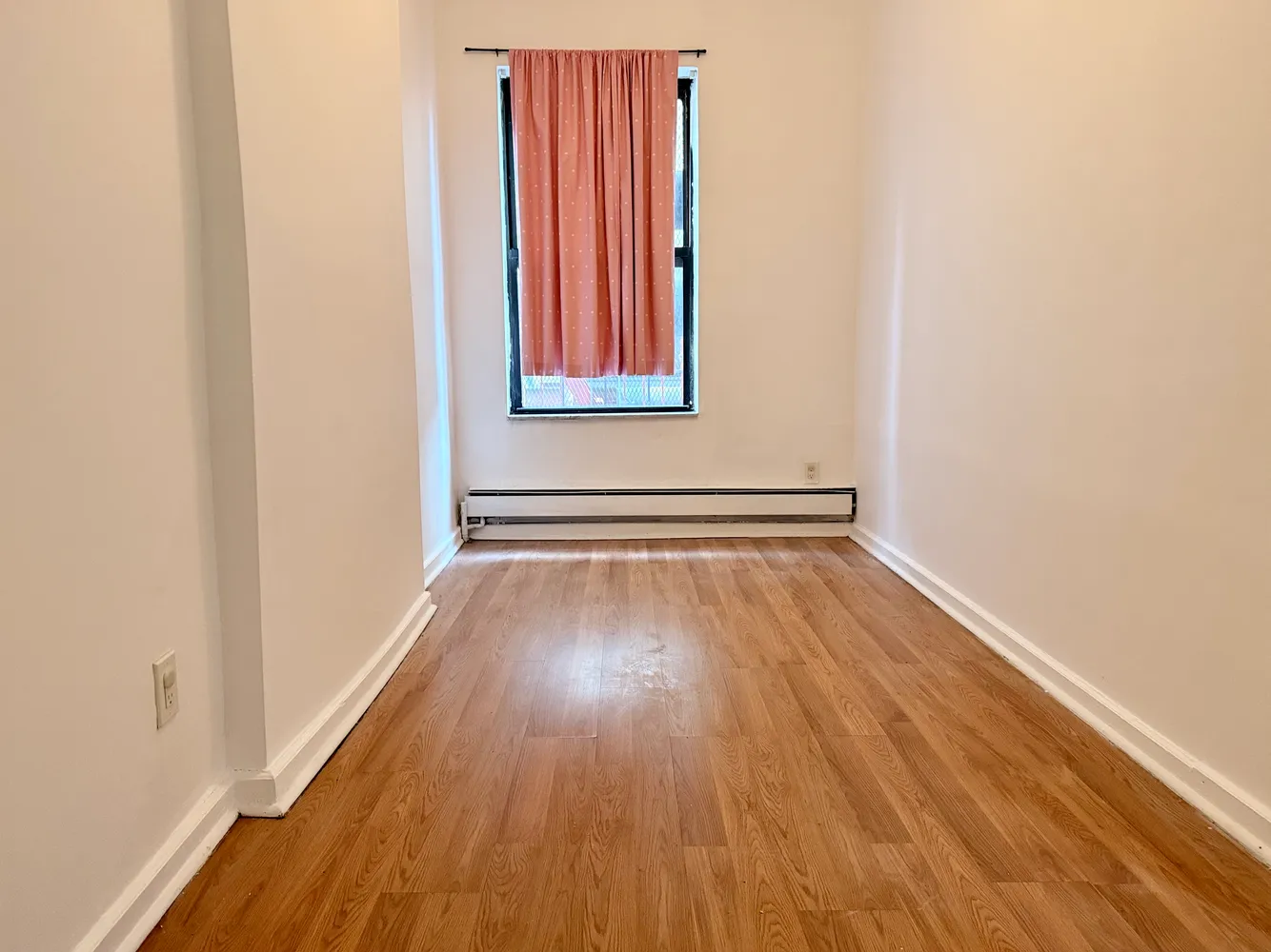 a view of a room with wooden floor and a window