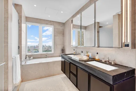 a bathroom with a two sinks a large mirror and a bathtub next to a window