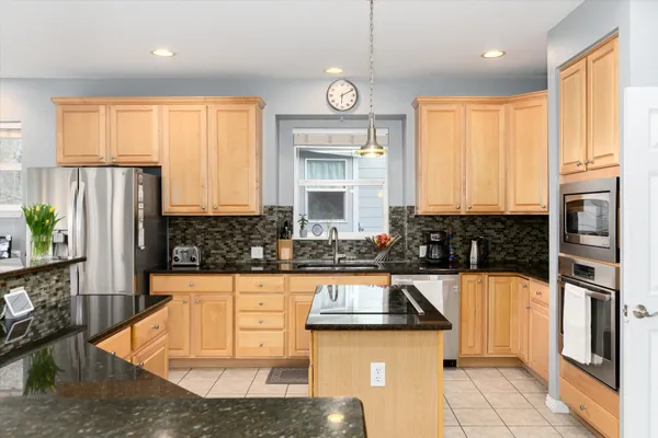 a kitchen with stainless steel appliances granite countertop a refrigerator a stove and a sink with wooden floor