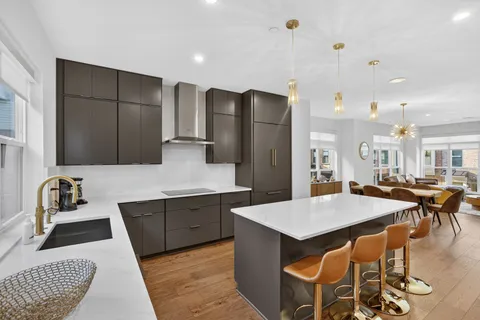a kitchen with stainless steel appliances kitchen island granite countertop a table chairs and a refrigerator