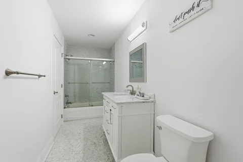a bathroom with a granite countertop sink a toilet and shower