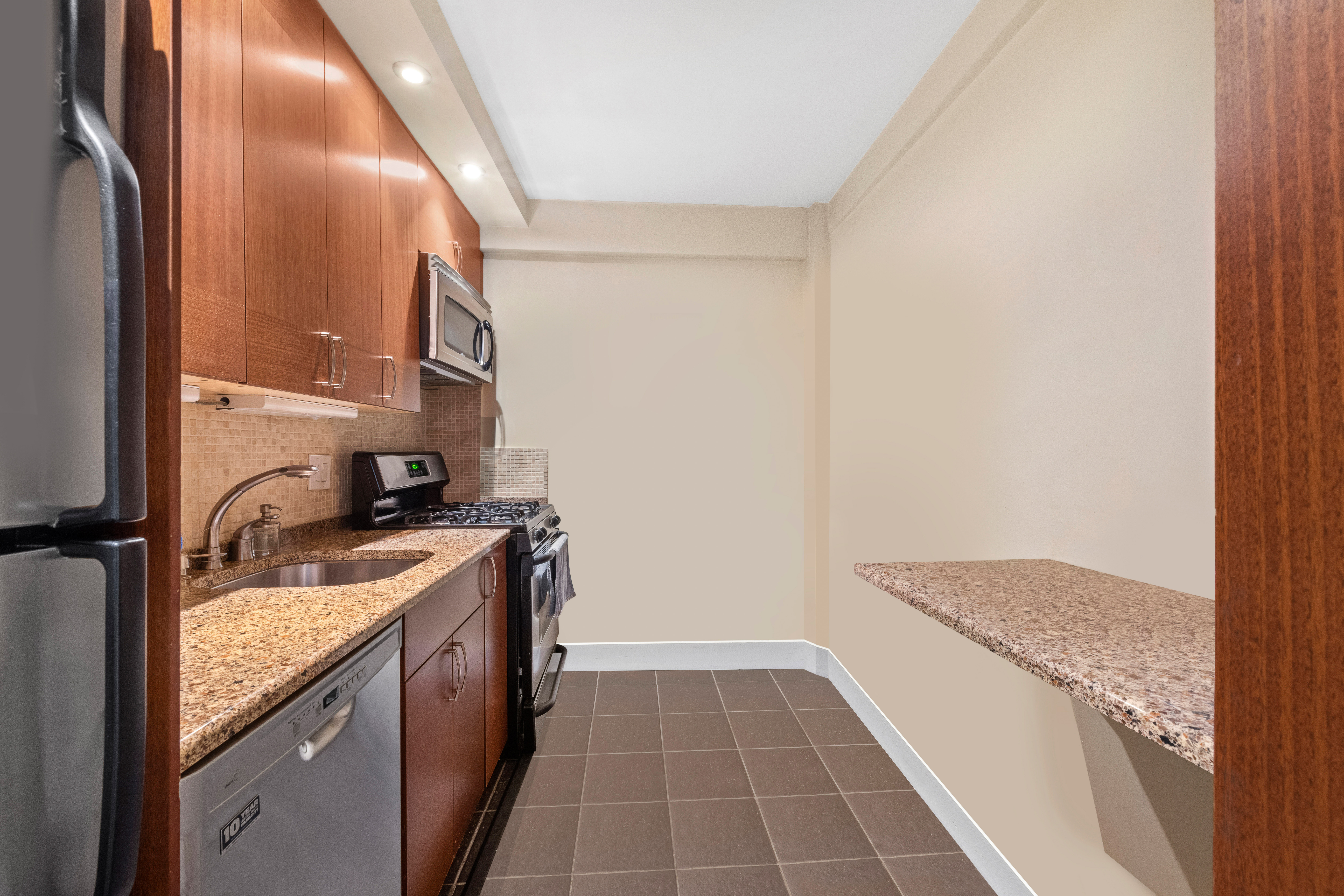 315 East 69th Street, Unit 4K Manhattan, NY 10021 - Photo 4 of 8 a kitchen with a sink and a refrigerator
