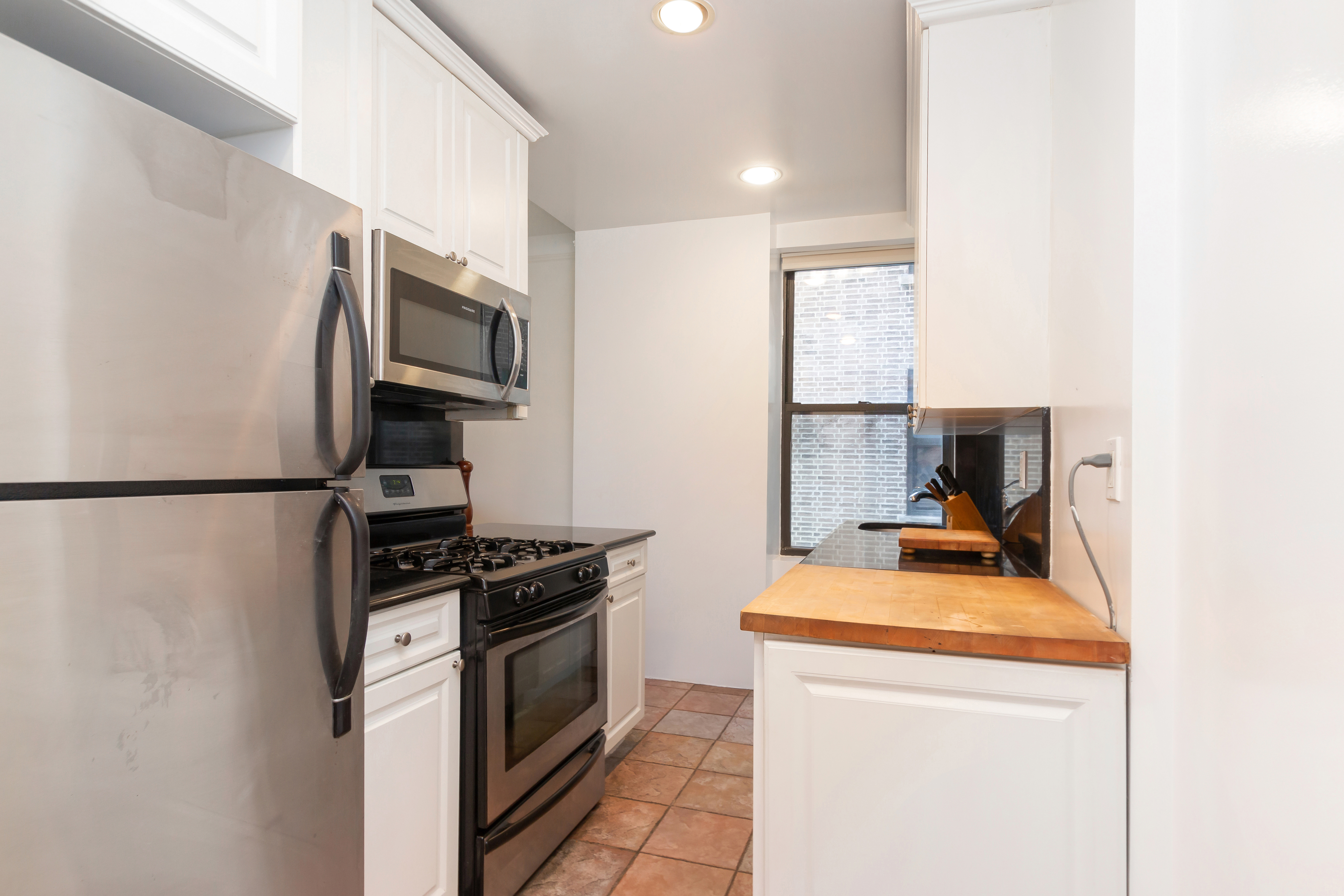801 Riverside Drive, Unit 4F Manhattan, NY 10032 - Photo 7 of 13 a kitchen with stainless steel appliances a stove a microwave and a refrigerator