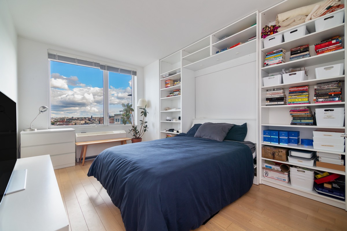 22 North 6th Street, Unit 18D Brooklyn, NY 11249 - Photo 6 of 9 a room with a bed furniture and a book shelf