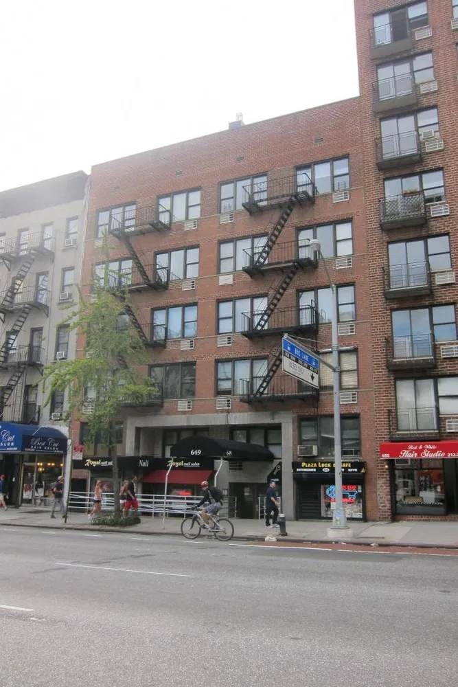 a front view of a building with lot of cars and trees