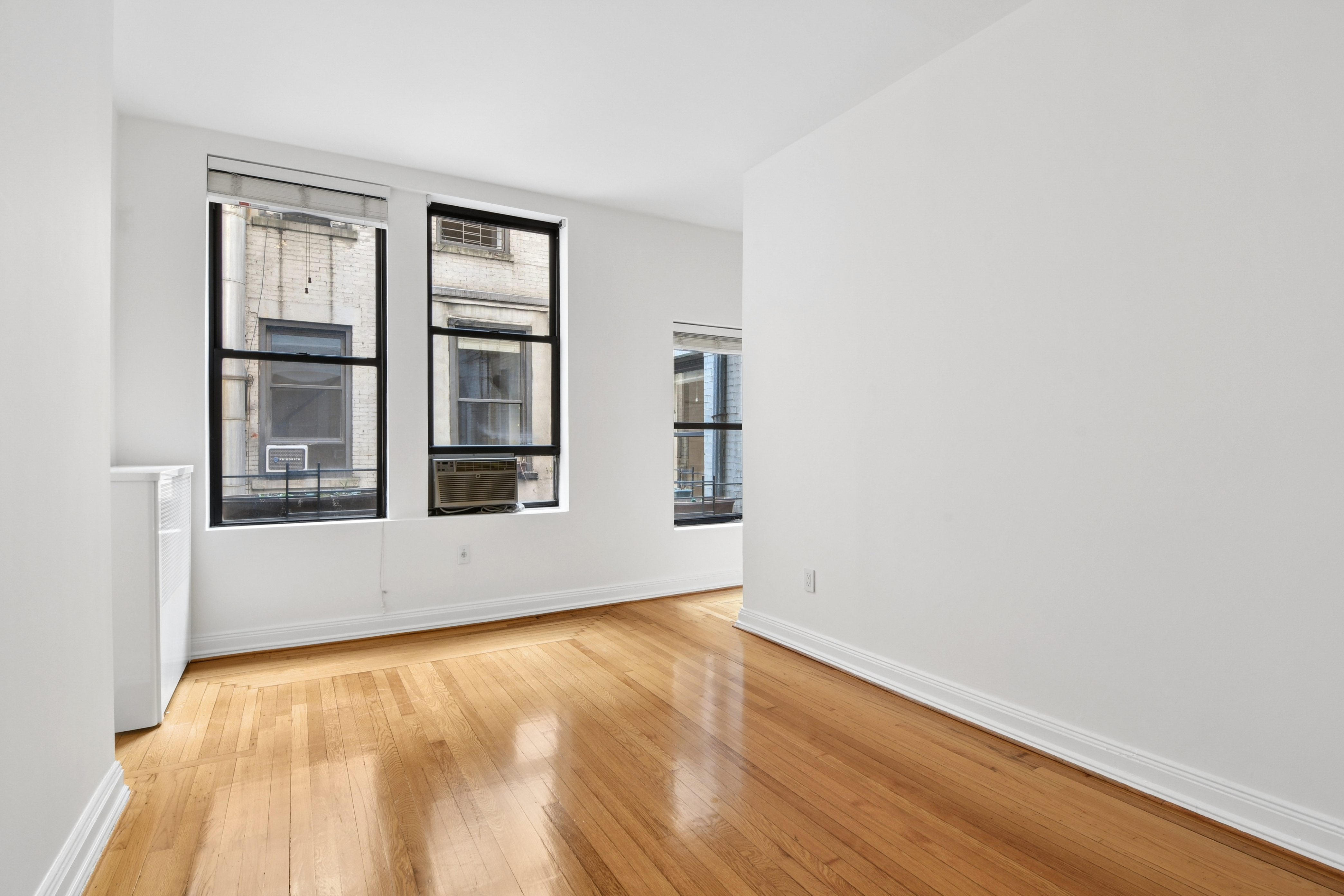 109 East 38th Street, Unit 3A Manhattan, NY 10016 - Photo 7 of 13 a view of an empty room with wooden floor and a window