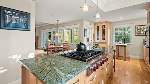 a kitchen with a stove a sink dishwasher and a dining table with garden view