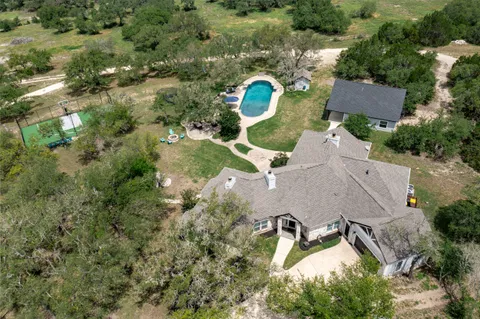 an aerial view of residential house with outdoor space and trees all around