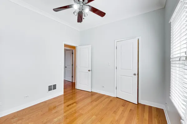 an empty room with wooden floor closet and windows