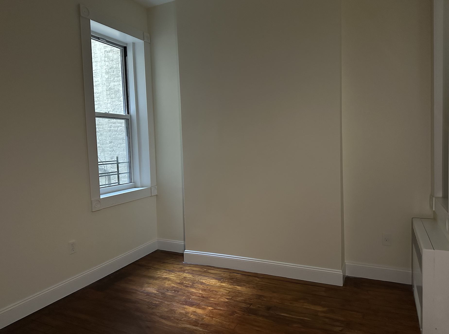 459 West 35th Street, Unit 1E Manhattan, NY 10001 - Photo 11 of 18 a view of an empty room with wooden floor and a window