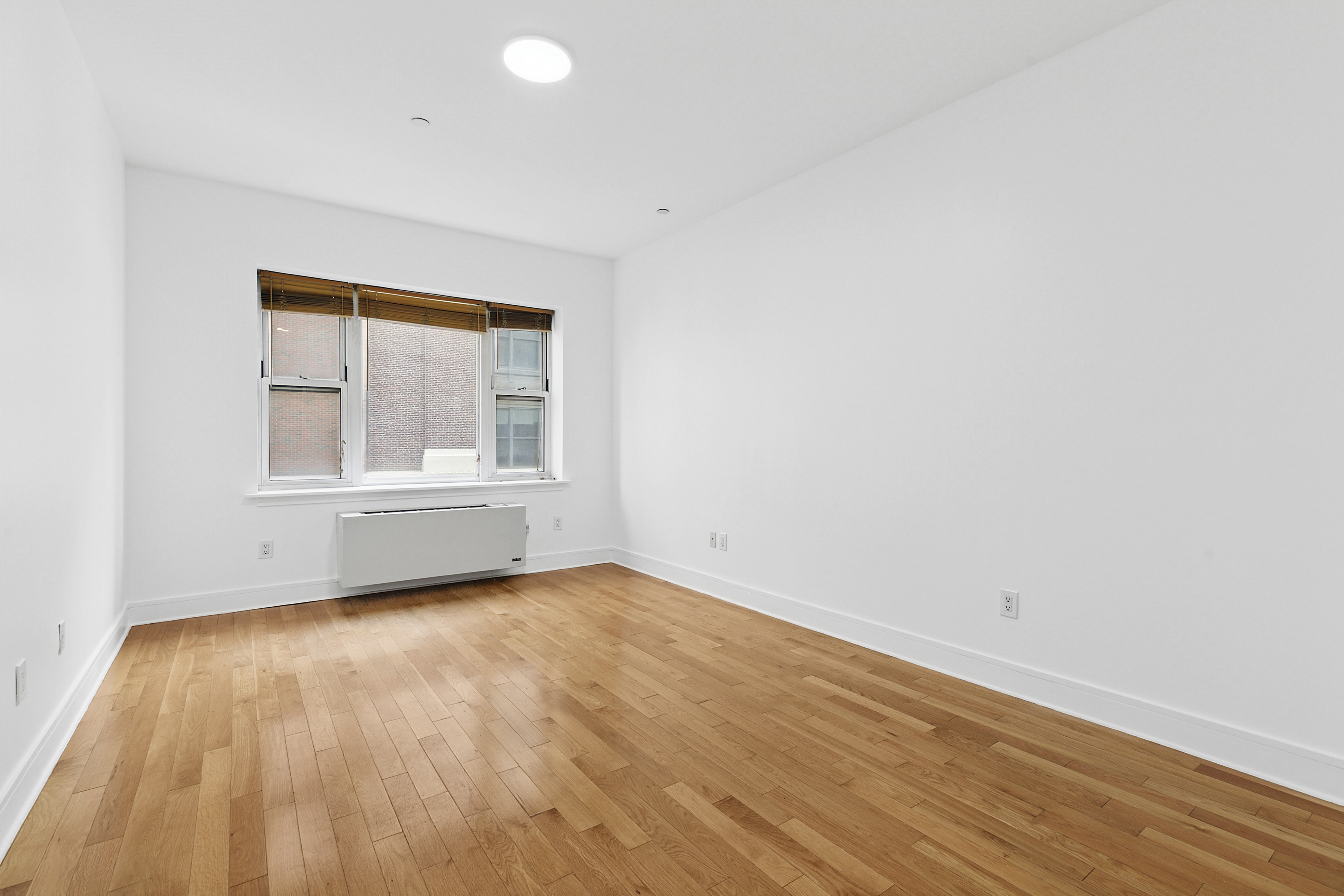 41-26 27th Street, Unit 4H Queens, NY 11101 - Photo 6 of 21 an empty room with wooden floor and windows