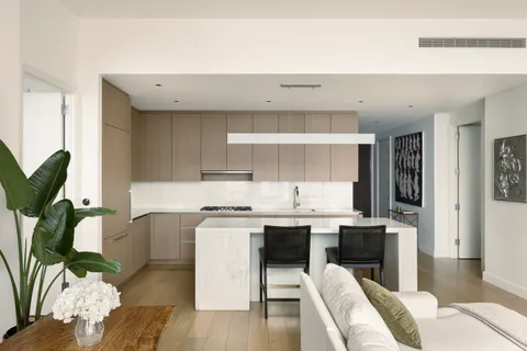 a living room with stainless steel appliances furniture a rug and a kitchen view