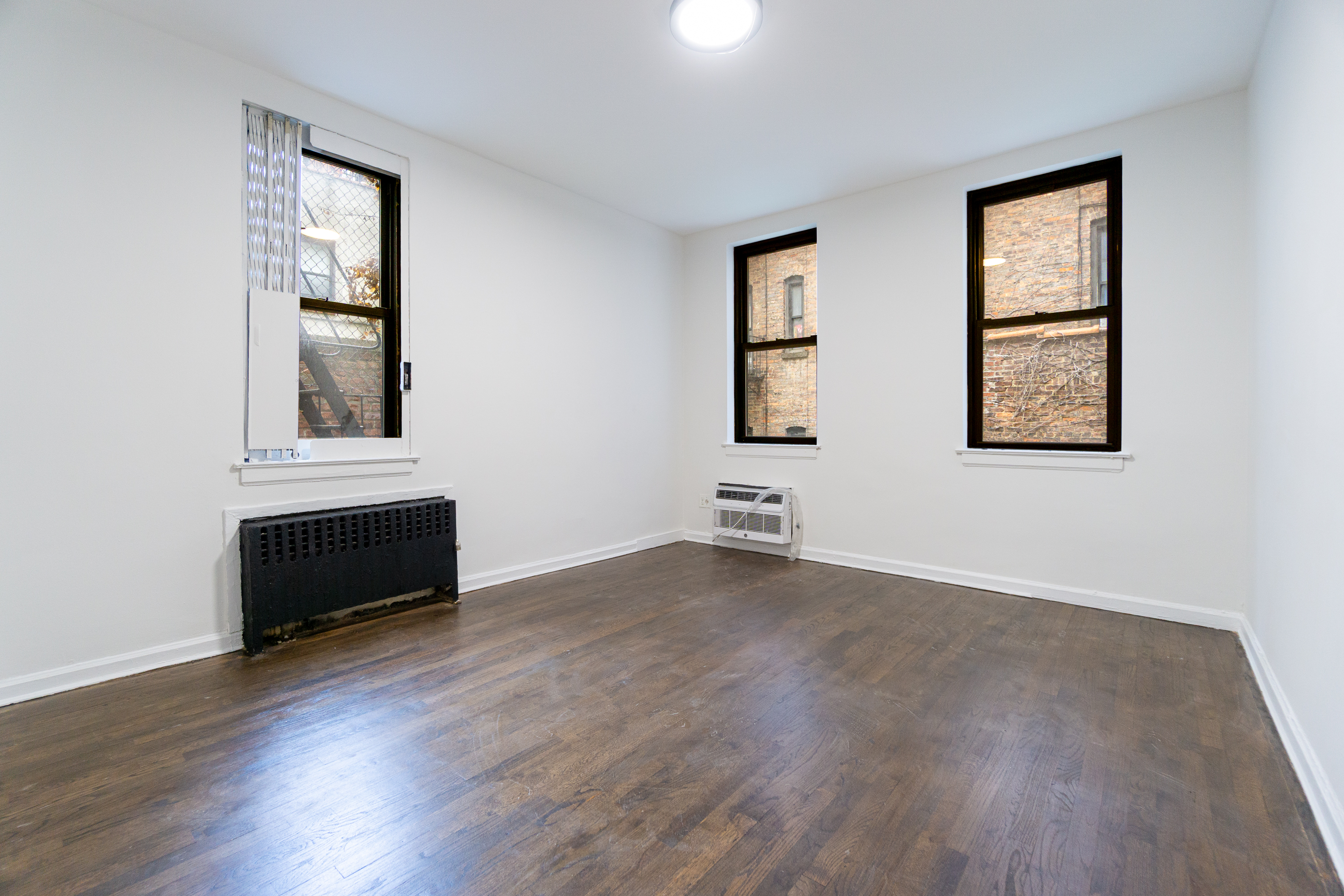 205 2nd Avenue, Unit 2C Manhattan, NY 10003 - Photo 3 of 15 an empty room with wooden floor and windows
