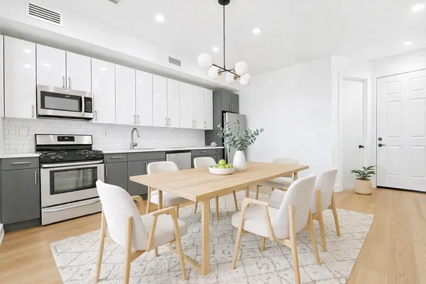 a kitchen with stainless steel appliances kitchen island granite countertop a dining table chairs and a refrigerator