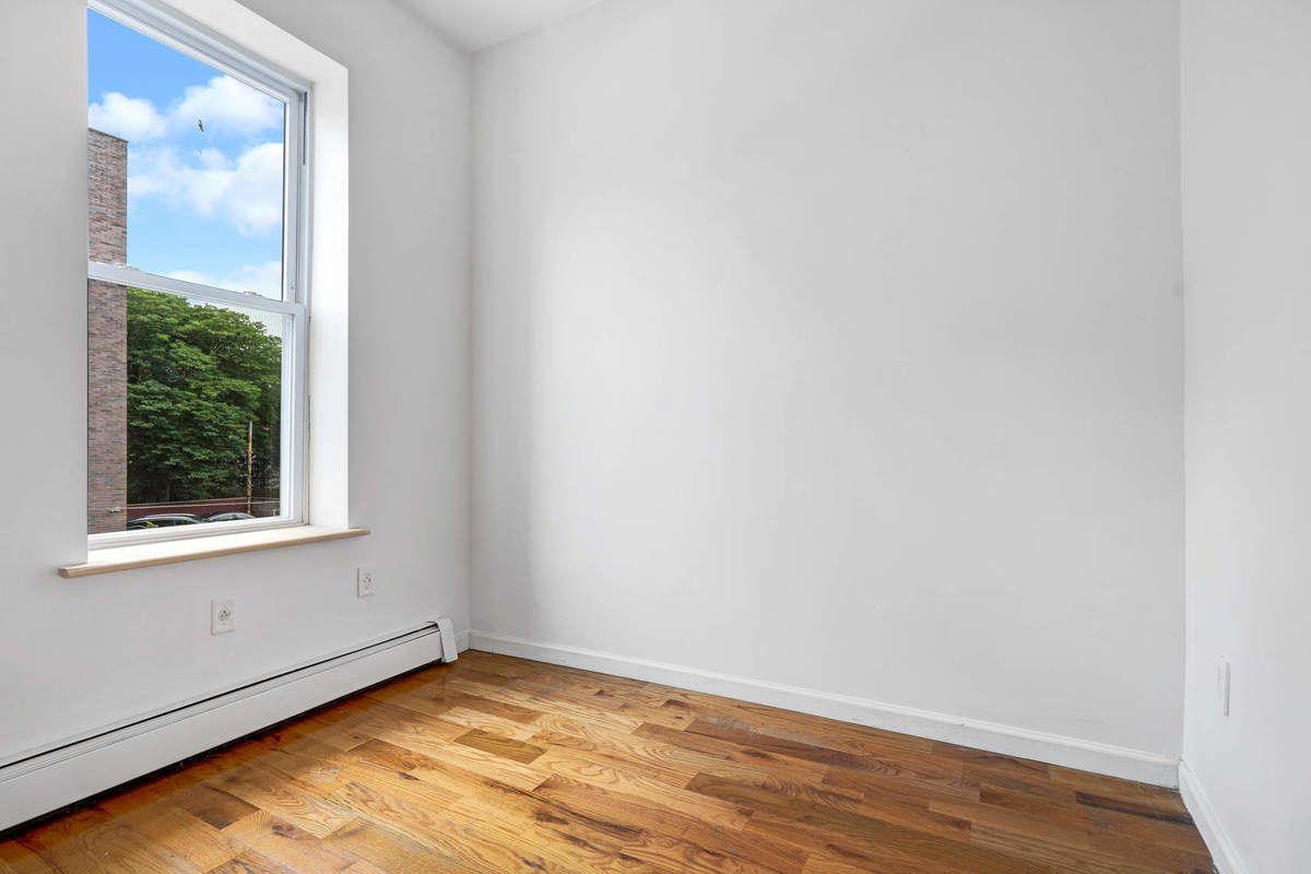 1235 Decatur Street, Unit 2 Brooklyn, NY 11207 - Photo 10 of 13 a view of an empty room with wooden floor and a window