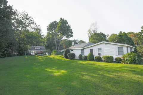a view of a house with a big yard plants and large trees