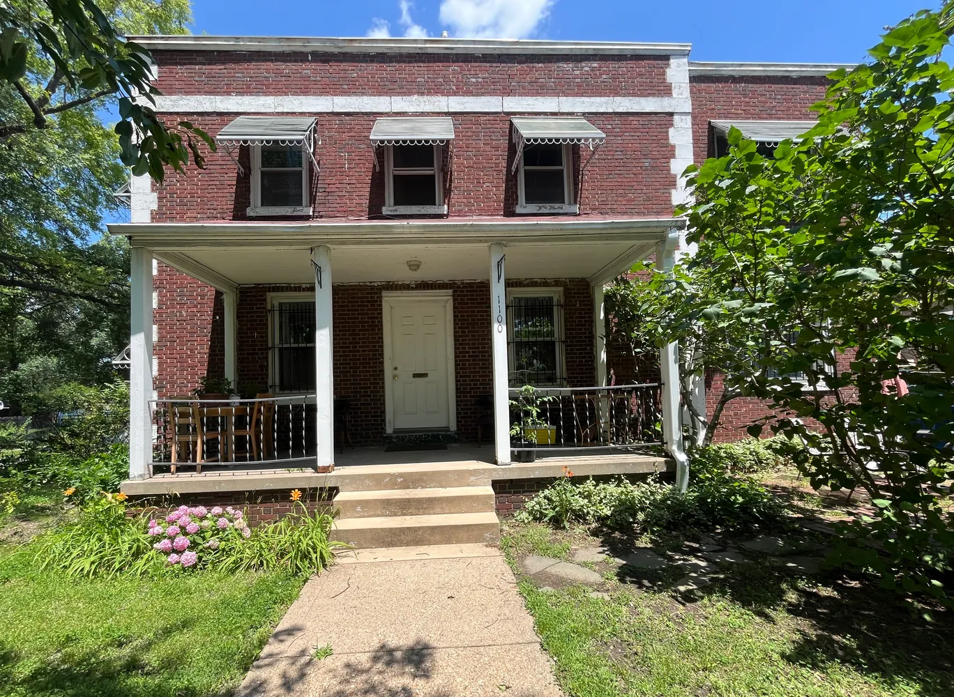 a view of a house with potted plants and a large tree