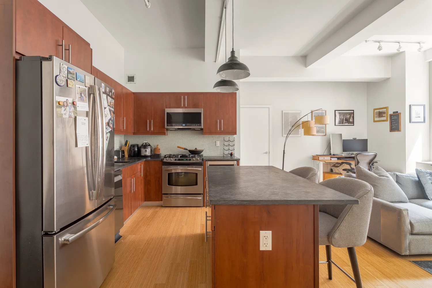 a kitchen with stainless steel appliances granite countertop a refrigerator a stove a sink a dining table and chairs with wooden floor