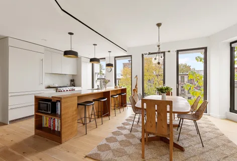 a kitchen with stainless steel appliances a stove a sink a counter top space and living room view