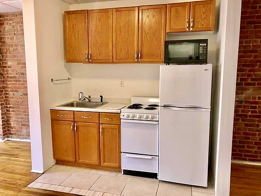 344 East 61st Street, Unit 12 Manhattan, NY 10065 - Photo 4 of 10 a kitchen with stainless steel appliances white cabinets and a refrigerator