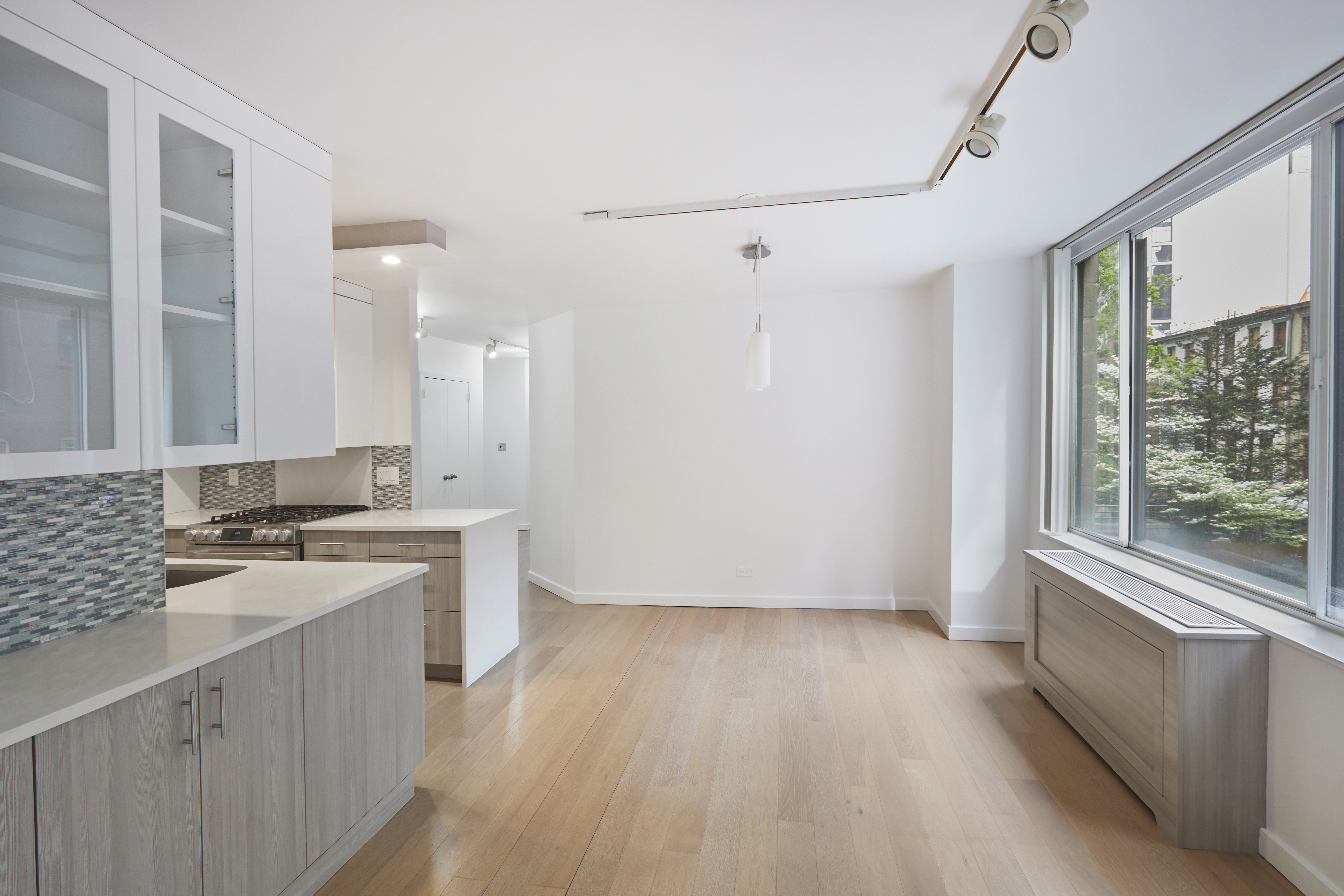 309 East 49th Street, Unit 3D Manhattan, NY 10017 - Photo 2 of 11 a view of a kitchen with a sink wooden cabinets and a window