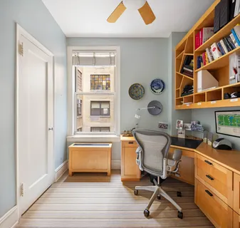 a view of a workspace with furniture and a window